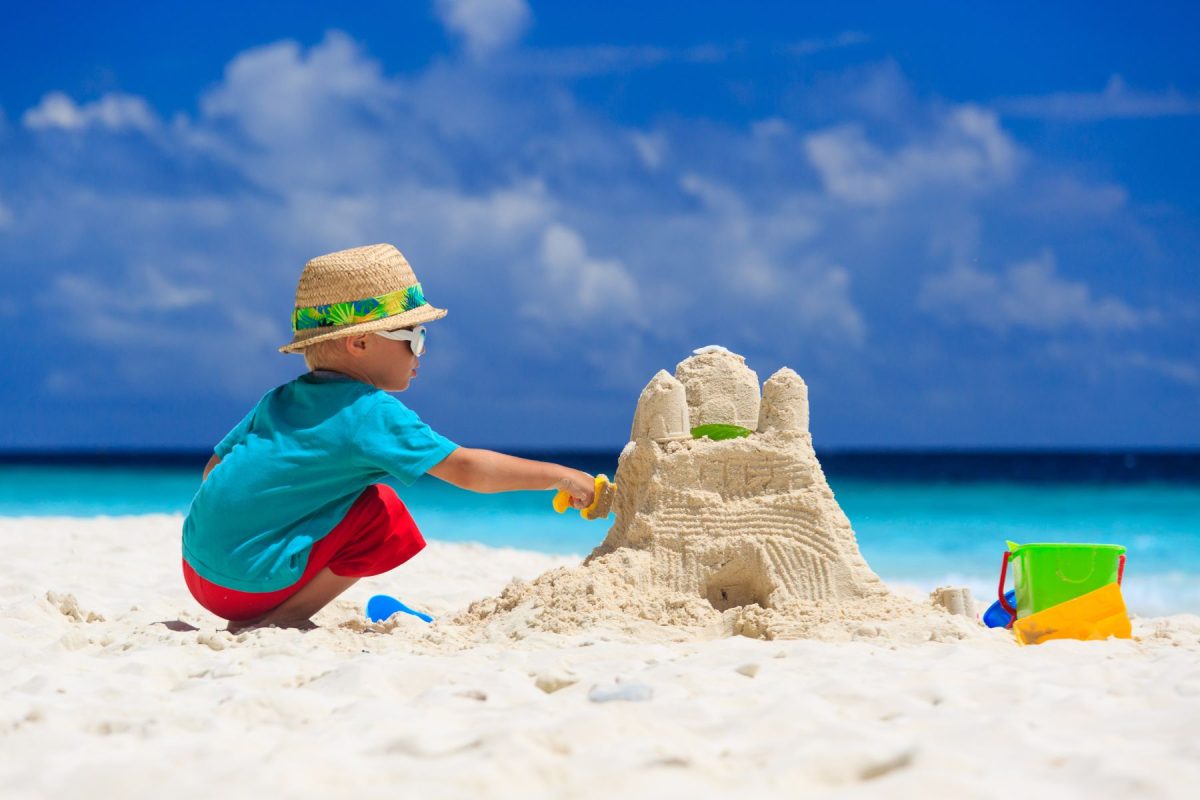 little boy builds sand castle on beach